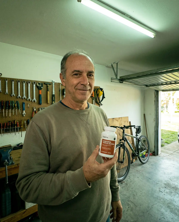 Hombre sosteniendo el frasco de Cúrcuma Triple Acción en el garaje de su casa
